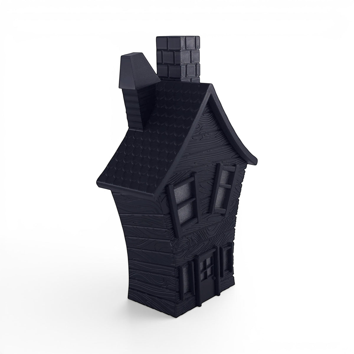 Black PLA flickering haunted house decoration with textured wood grain finish, crooked chimney, and window details. Front left corner of house.