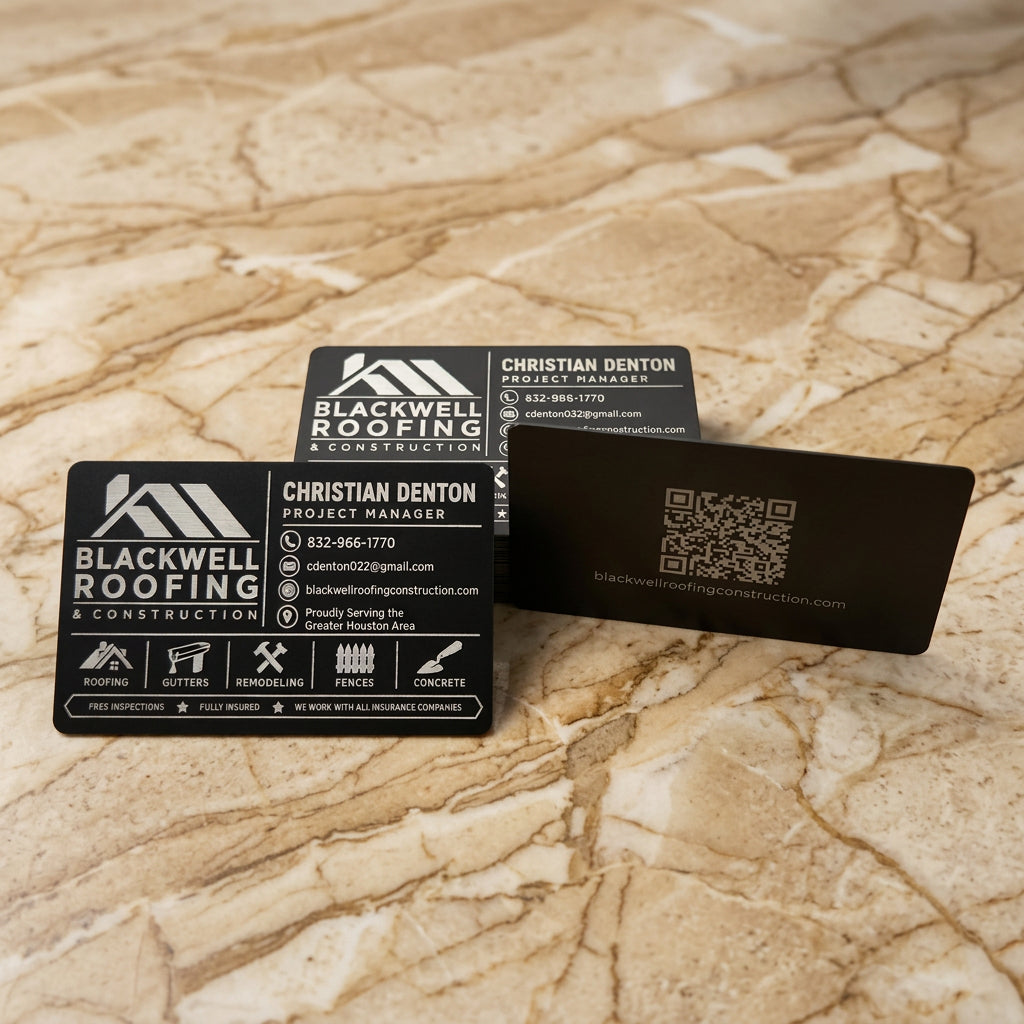 Three black business cards for Blackwell Roofing & Construction are displayed on a clean white background. One card is shown from the front with company logo, contact info, and icons; another shows the back with a QR code and website; the third is partially visible behind them.