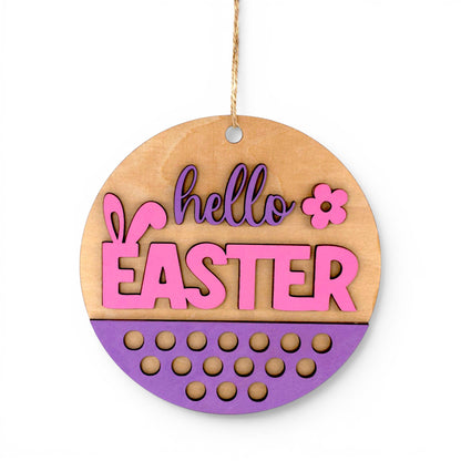 Round Easter Hanging Wood Sign with pink and purple "hello EASTER" lettering, bunny ears, and floral accent. Front view of sign.