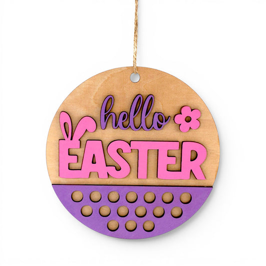 Round Easter Hanging Wood Sign with pink and purple "hello EASTER" lettering, bunny ears, and floral accent. Front view of sign.