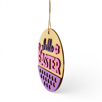 Round Easter hanging wood sign with "hello EASTER" in pink and purple, bunny ears, and purple speckled pattern. Front right view of sign.
