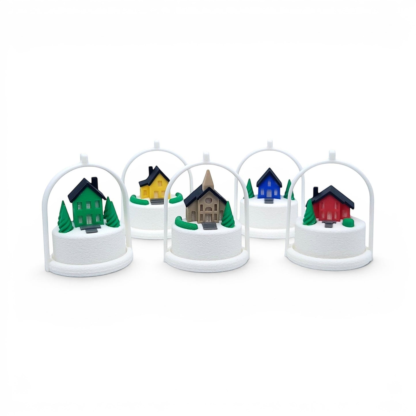 Miniature winter village ornaments with colorful houses and snowy bases in white arched frames. Front view of all five houses, in tree stands with light off.