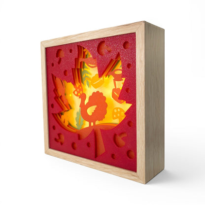 Thanksgiving Leaf Layered Lightbox with turkey, pumpkins, mushrooms, and fall foliage. Light faux wood frame. Front right view of box with led light on.
