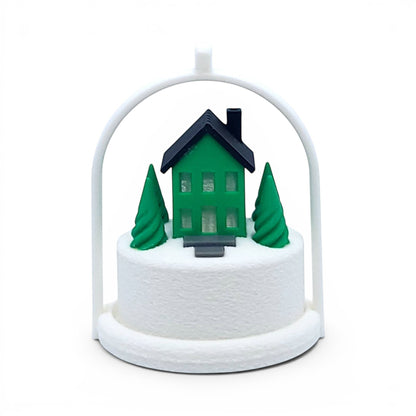 Miniature winter village ornament with a green house, pine trees, and white arched frame. Front view of green house, inside the tree stand with light off.