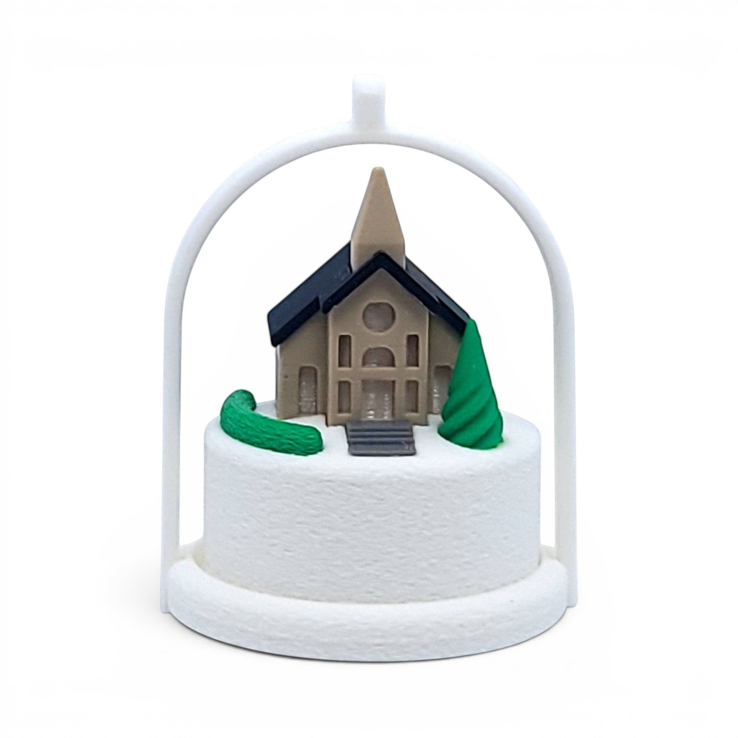 Miniature winter village church ornament with a white arched frame and snowy base. Front view of brown church, in tree stand with light off.