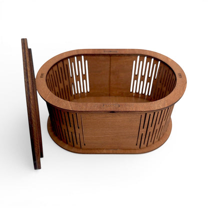 Oval wooden keepsake box with laser-cut slatted sides and matching lid for jewelry storage. Front top view of box with lid off sitting next to the box.
