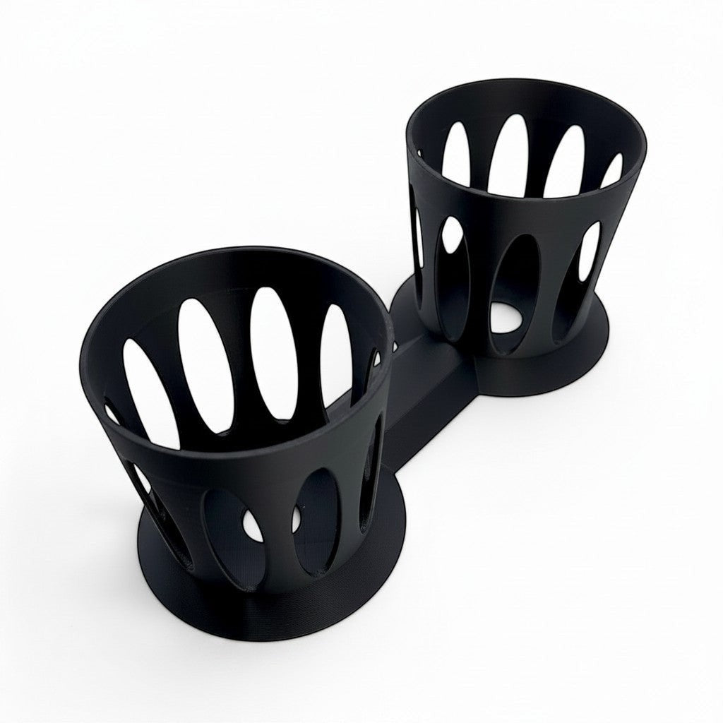 black dual cup holder made of lightweight PLA plastic with an open-vented design for mixing drinks. top down view with holder on side.