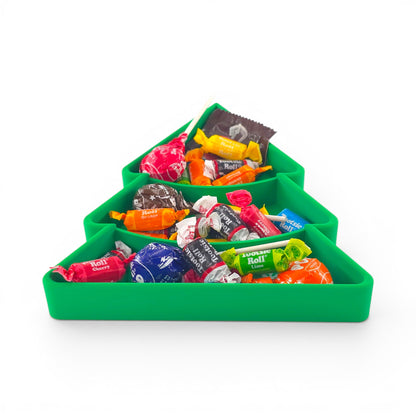 Green Christmas tree candy serving tray with tiered compartments filled with assorted wrapped candies. Front angle of tray filled with candy.