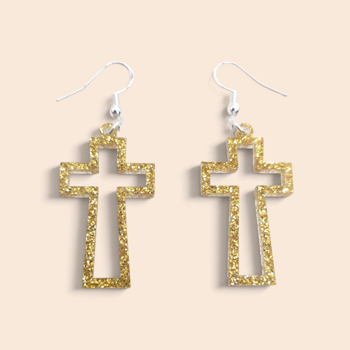 gold glitter open-frame cross dangle earrings with hypoallergenic hooks on a beige background.