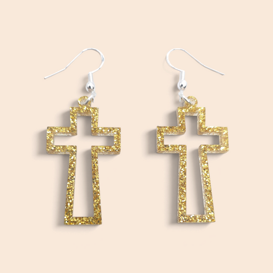 gold glitter open-frame cross dangle earrings with hypoallergenic hooks on a beige background.