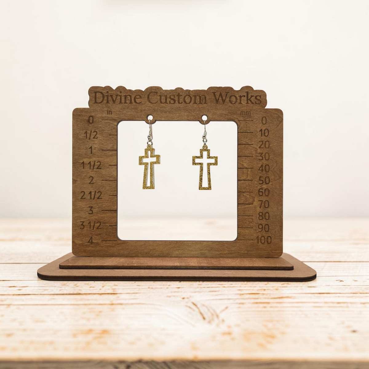 gold glitter open-frame cross dangle earrings with hypoallergenic hooks on a wooden sizing display stand.