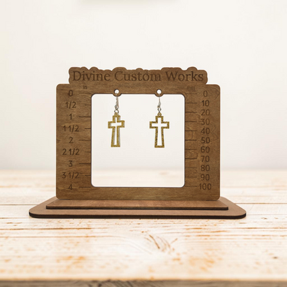 gold glitter open-frame cross dangle earrings with hypoallergenic hooks on a wooden sizing display stand.