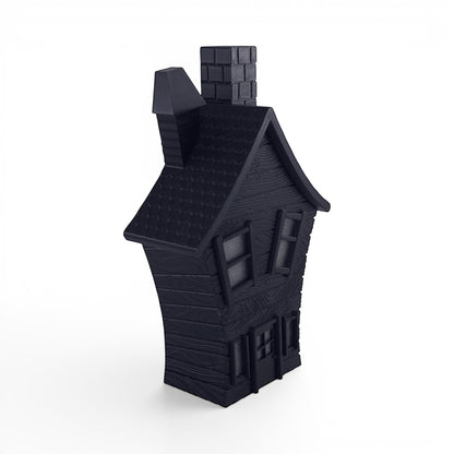 Black PLA flickering haunted house decoration with textured wood grain finish, crooked chimney, and window details. Front left corner of house.