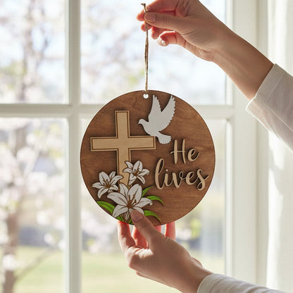 He Lives Easter wooden ornament with cross, lilies, and dove. Natural wood.