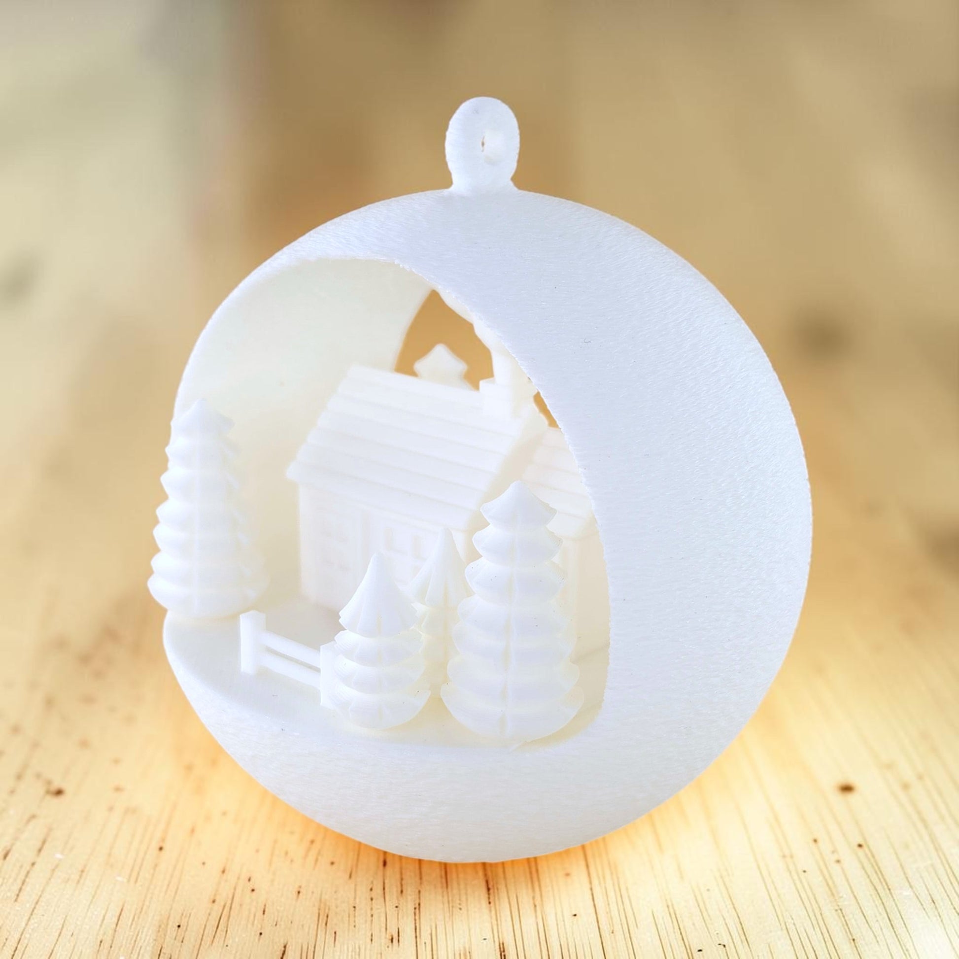 white PLA illuminated winter farmhouse ornament with trees and fence. Light off, front right of ornament.