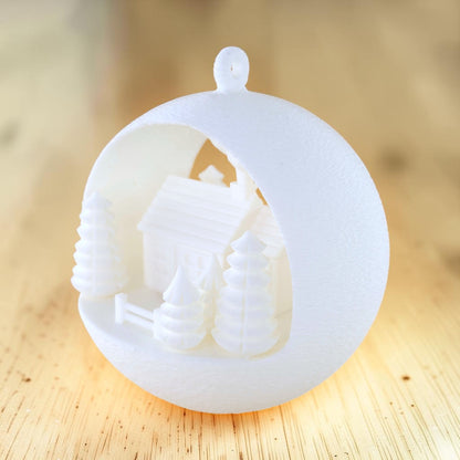 white PLA illuminated winter farmhouse ornament with trees and fence. Light off, front right of ornament.