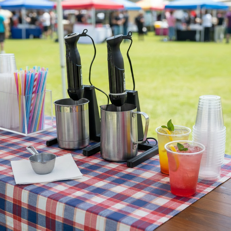 black immersion blender stands holding blenders in stainless steel pitchers on a picnic table