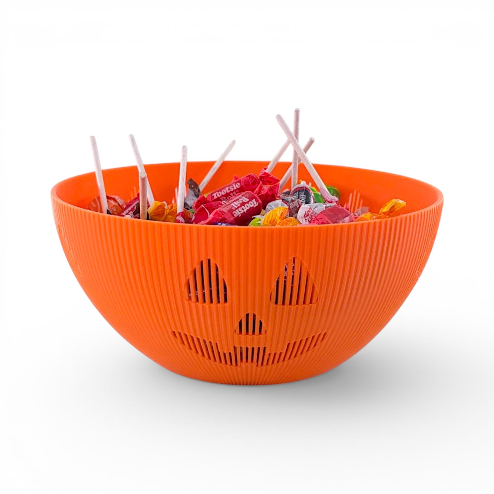 Orange PLA plastic Jack-o'-lantern candy bowl with carved face, filled with wrapped candies and lollipops. Front of bowl, filled.
