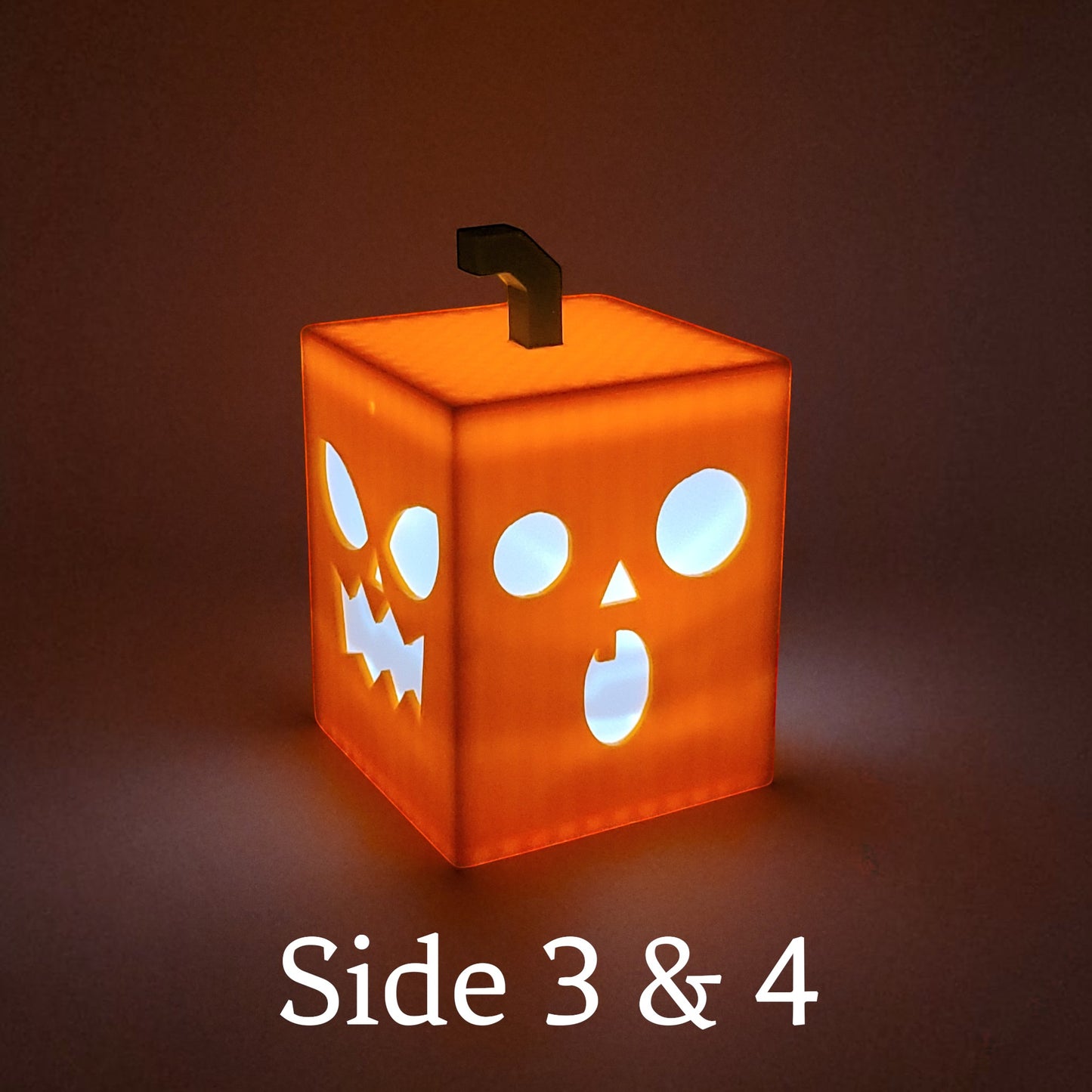 Orange PLA cube light with playful jack-o-lantern faces on each side, perfect for Halloween decor. L:ighted.