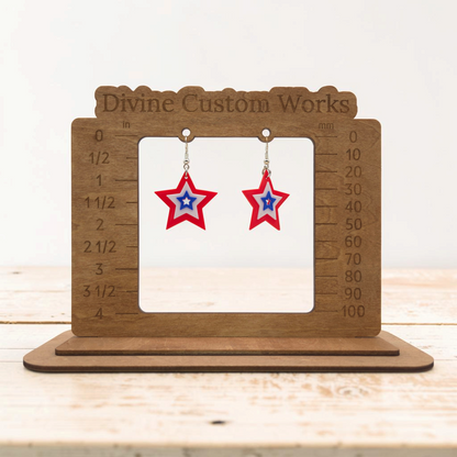 layered star dangle earrings in red, white, and blue on a wooden measurement display stand.