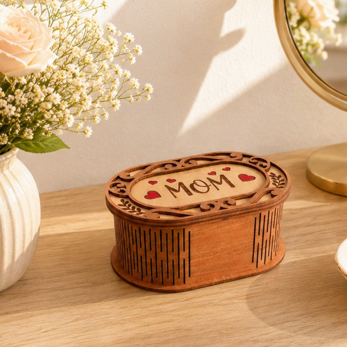 Oval wooden keepsake box with laser-cut MOM text and red heart accents on a vanity table. Box on vanity stand.