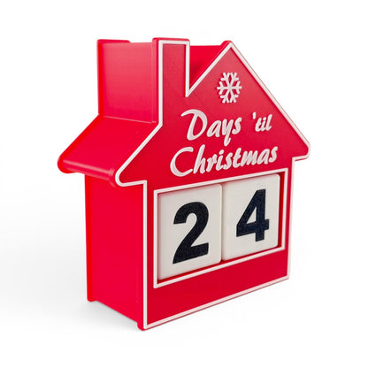 red house-shaped Christmas countdown advent calendar with rotating number blocks on a white base. Left side view of house with two blocks inside.