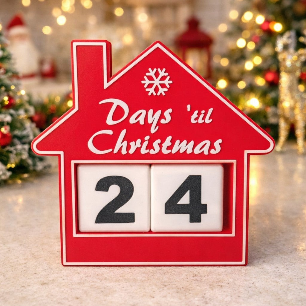 red house-shaped Christmas countdown advent calendar with rotating number blocks on a table. Advent calendar on a countertop with festive background.