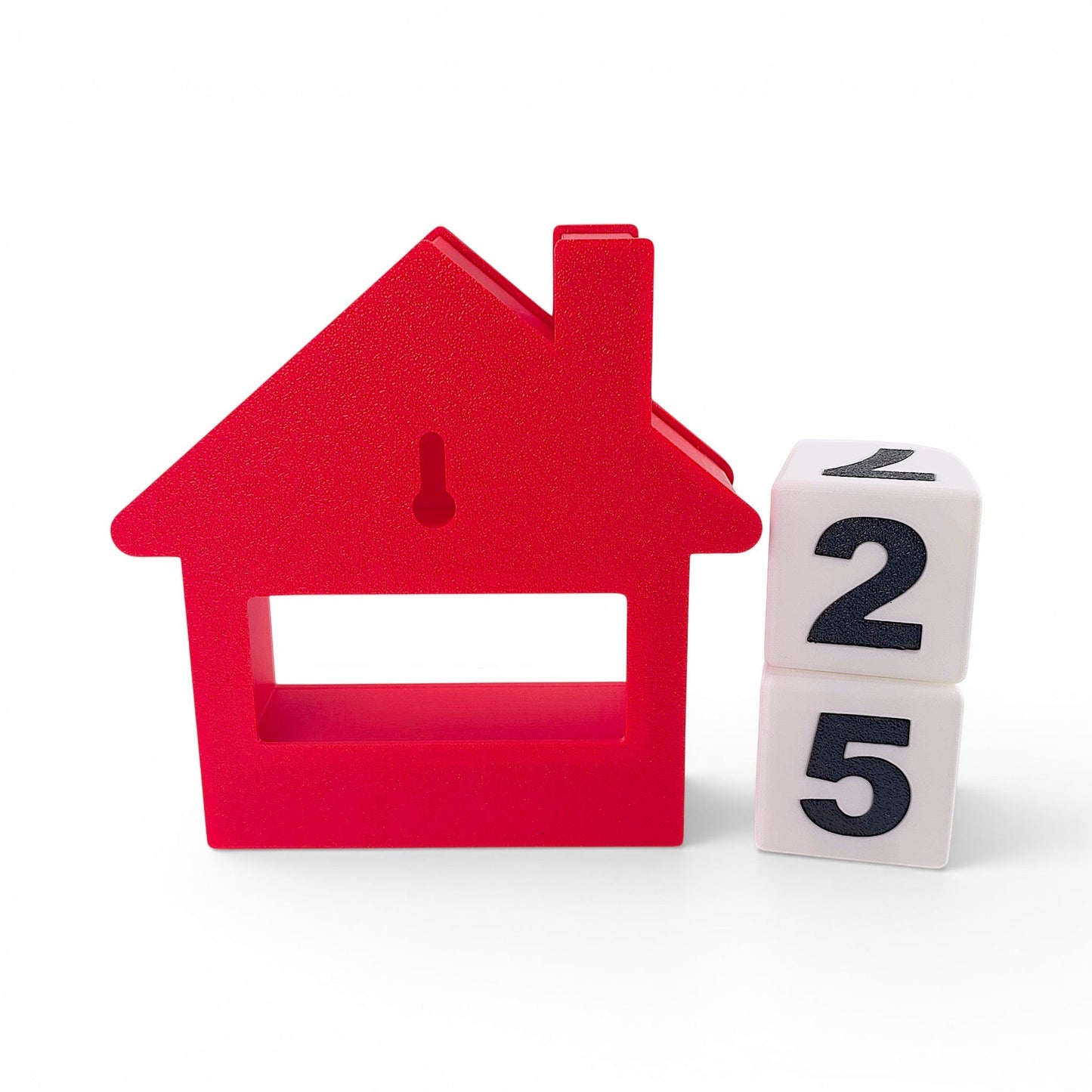 red house-shaped Christmas countdown advent calendar with white number blocks on a white background. Back view of house, two blocks outside of house stacked on top of one another.