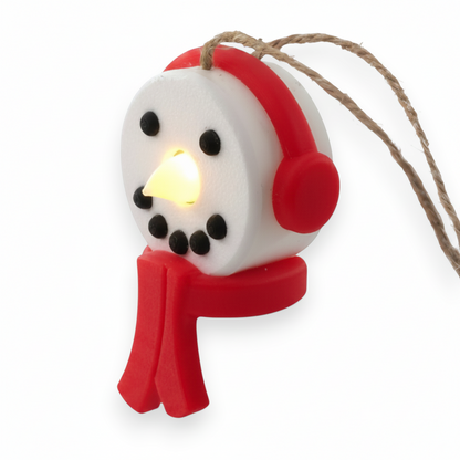 snowman tea light ornament with red headphones and scarf, glowing with a warm LED light