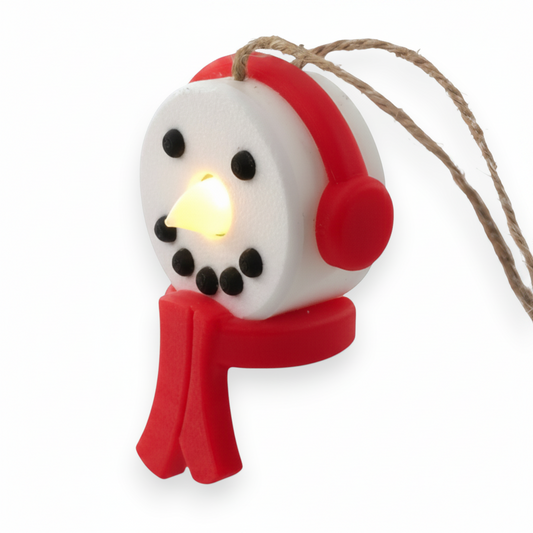 snowman tea light ornament with red headphones and scarf, glowing with a warm LED light