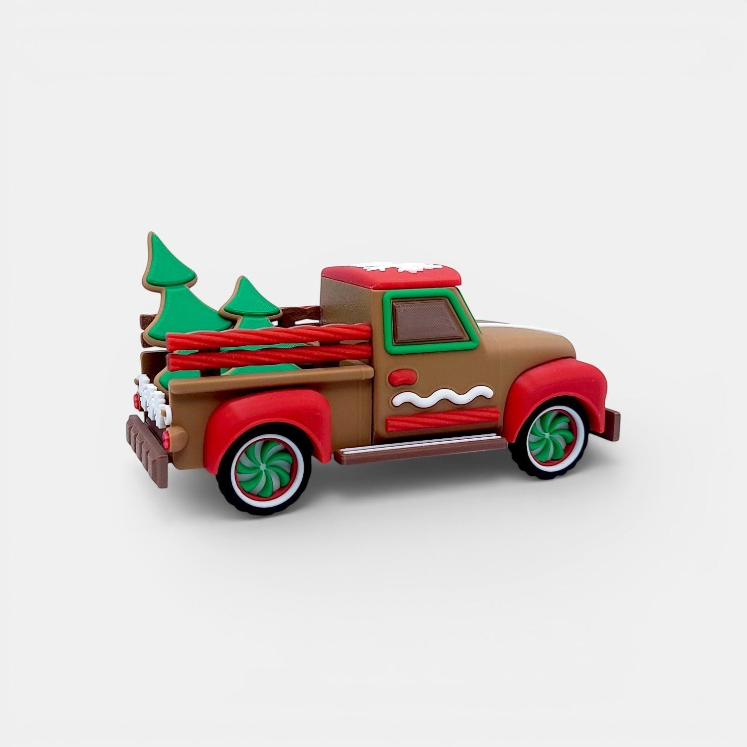 Vintage Christmas truck decoration with gingerbread accents, red wheels, and green trees.