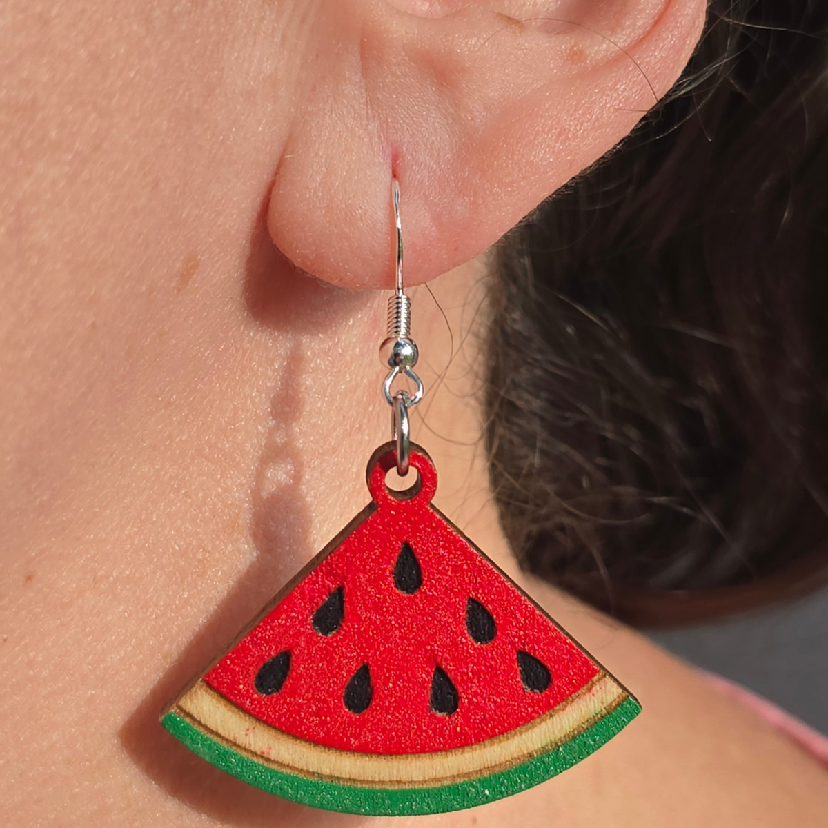 watermelon dangle earrings made from hand-painted basswood with hypoallergenic silver hooks hanging from ear lobe