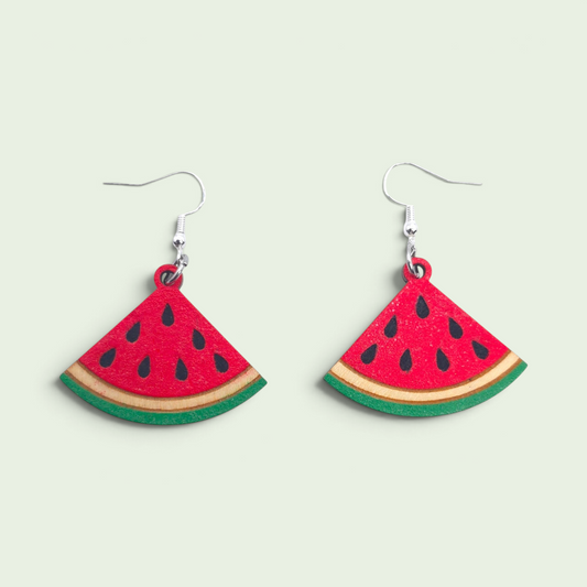 Watermelon slice dangle earrings made of sustainable wood with red, green, and black details. Watermelon front earring, laying on back.