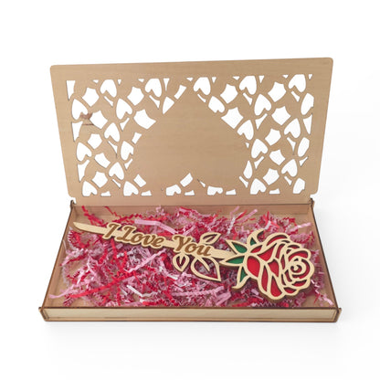 Wooden gift box with laser-cut hearts and a wooden rose inside. The rose has red petals and green leaves with "I Love You" etched on the stem.
